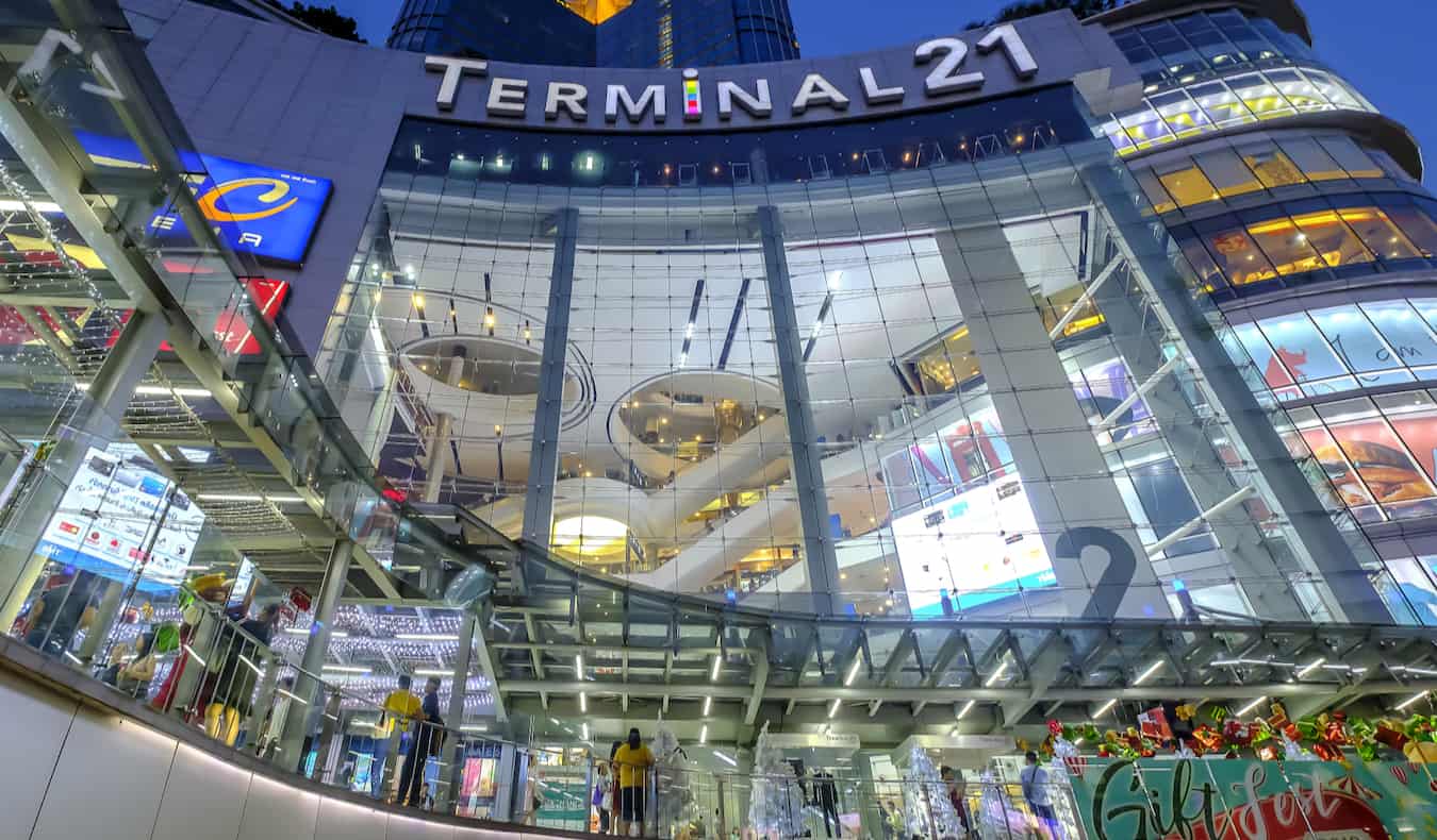 The towering exterior of the Terminal 21 shopping mall with people shopping in Bangkok, Thailand