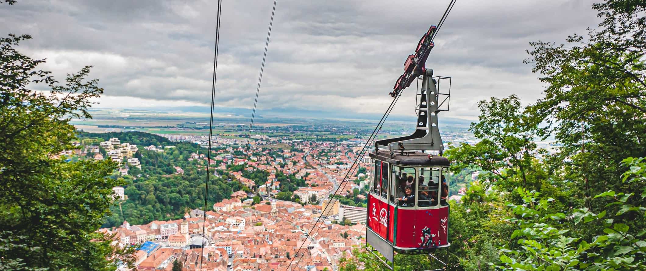 Cable car going up the mountain with the old town of Brasov, Romania in the background.