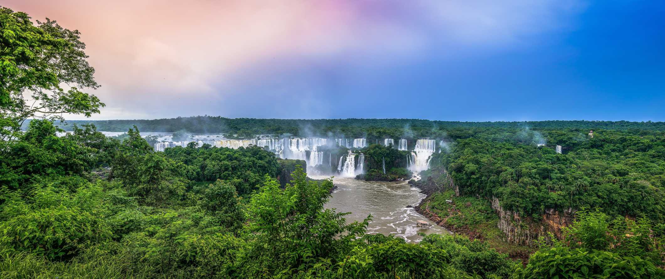 The expansive Iguazu Falls in Brazil within the lush rainforest at sunset