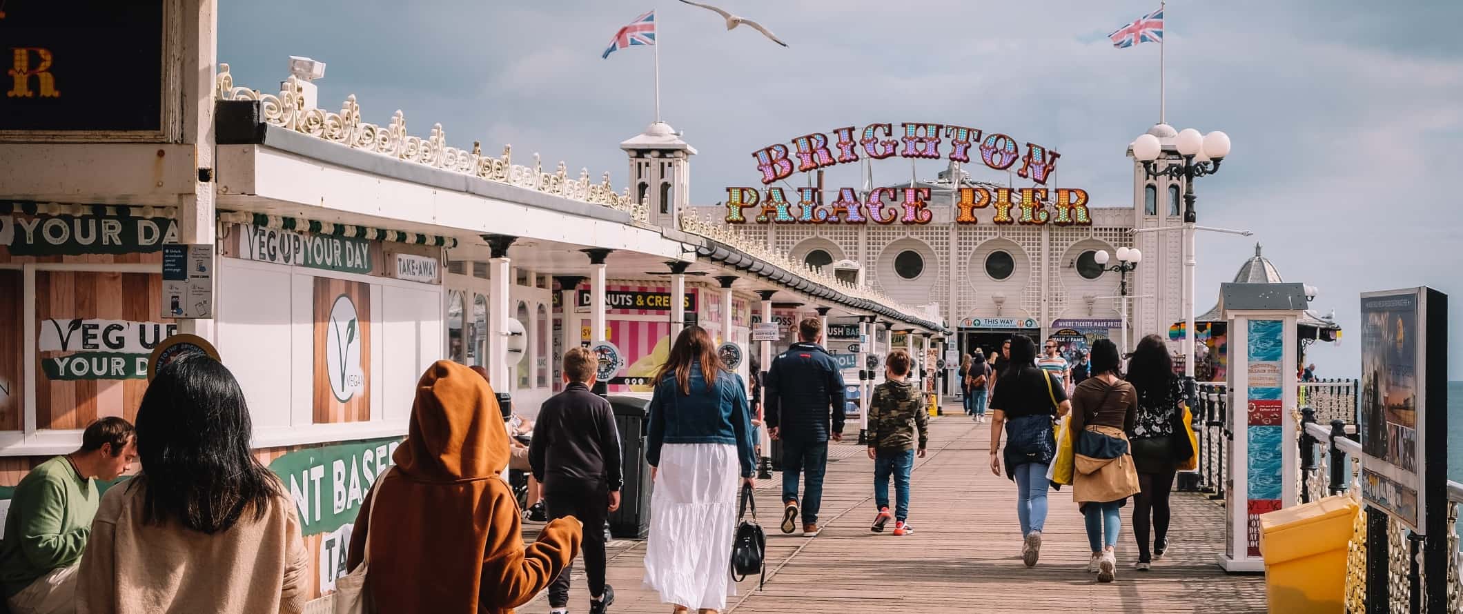 People walking around on the boardwalk on the Brighton pier in Brighton, UK