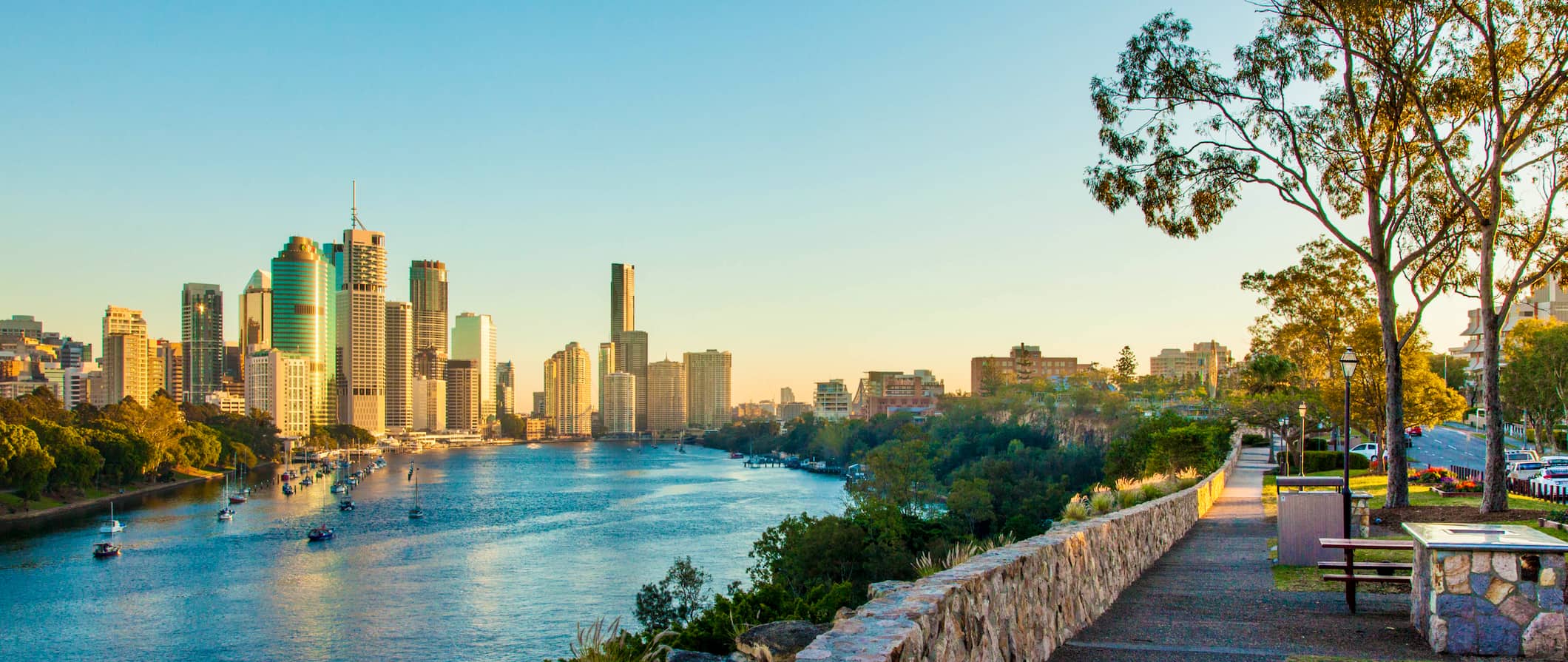 A relaxing walking path along the water in Brisbane, Australia with the towering skyline in the distance