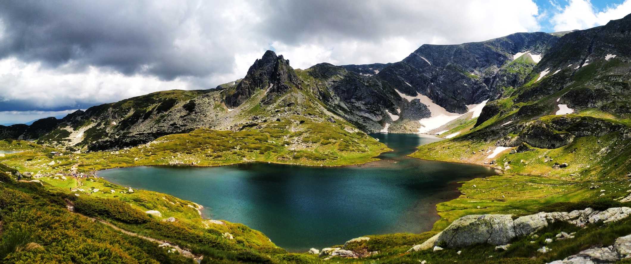 An emerald green lake with sharp jagged peaks in the background in the Rila Mountains, Bulgaria