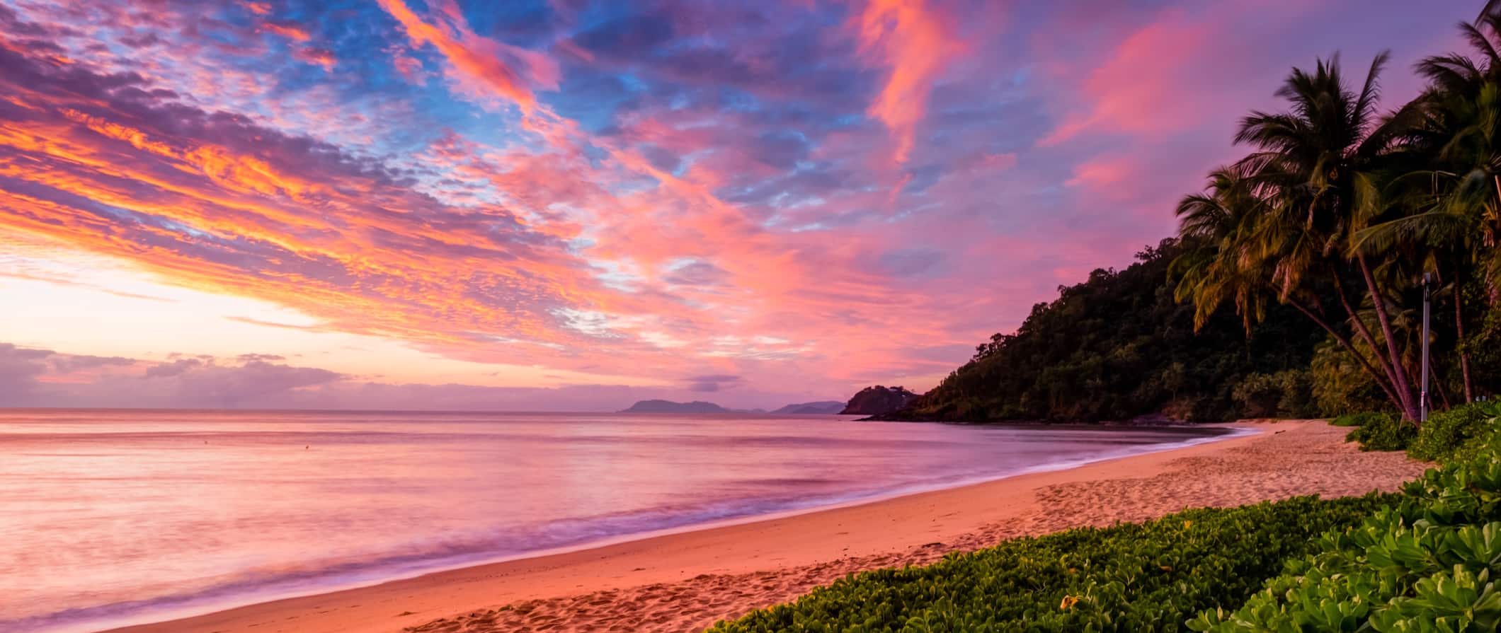 A vivid, pink sunset along the water in Cairns, Australia
