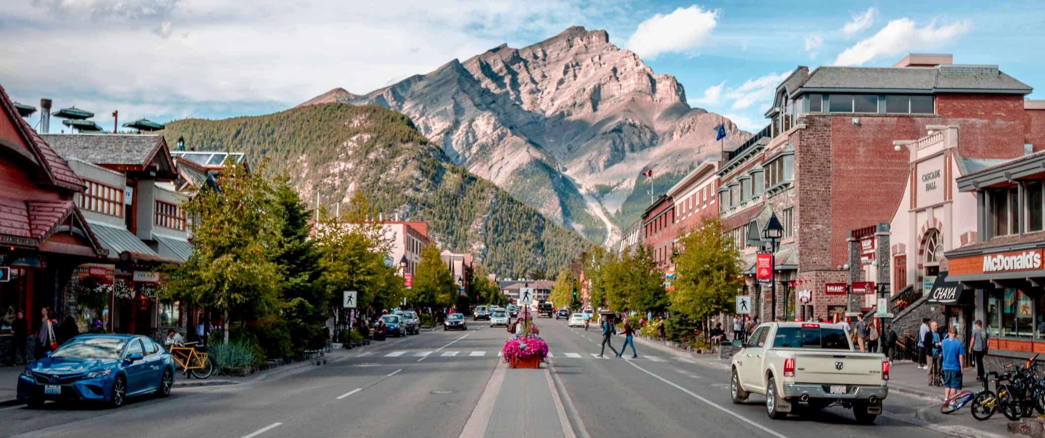 A quiet street in Banff, Alberta with towering mountains in the distance