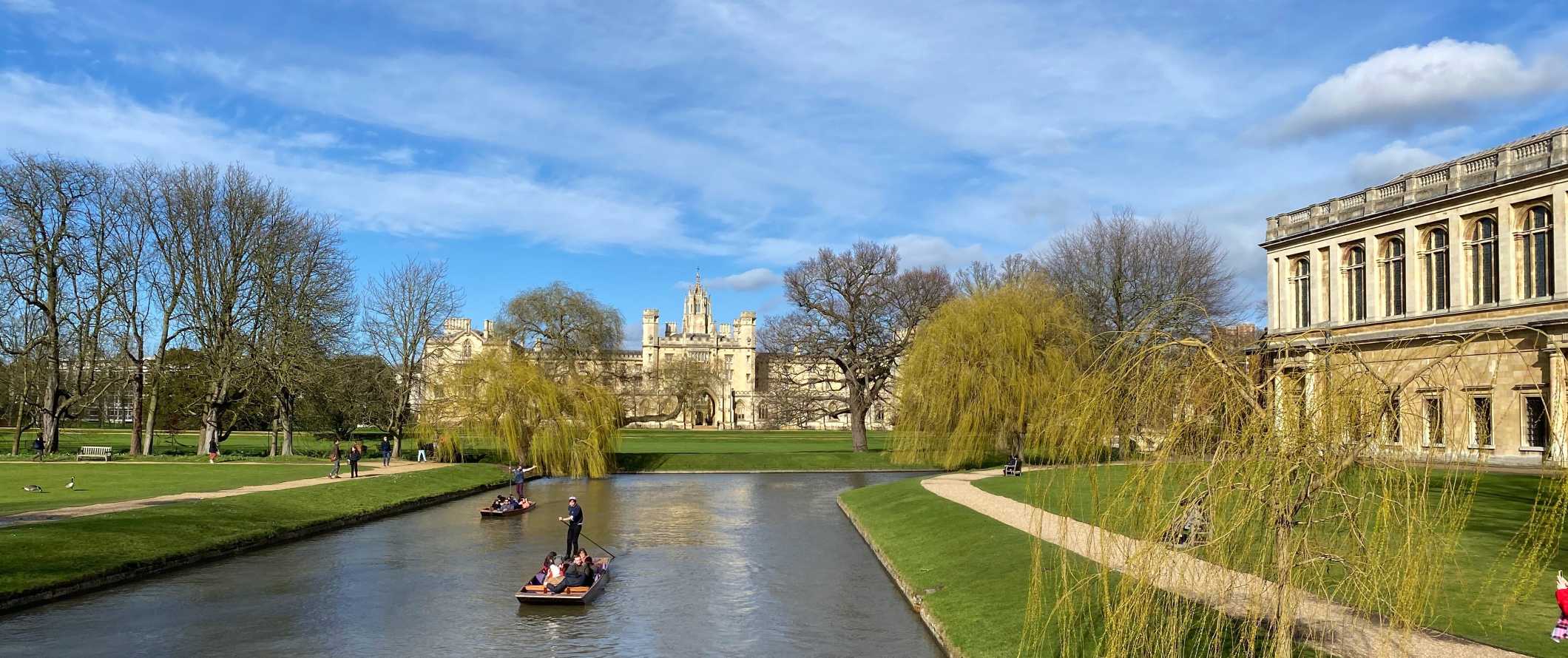 People punting down the river with the buildings of Cambridge University in the background in Cambridge, England