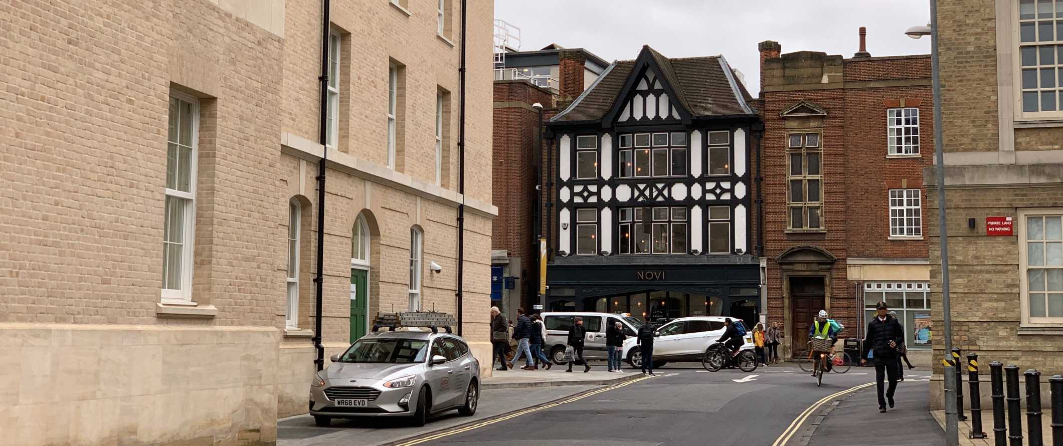 Street scene with a historic Tudor-style building in the background in Cambridge, England