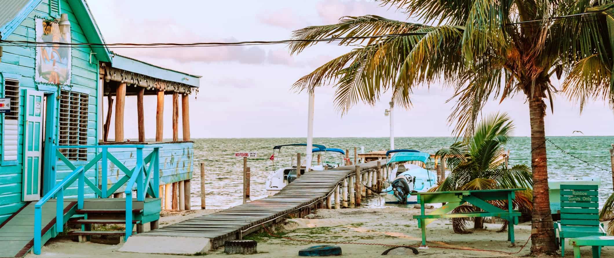 Turquoise colored house along the beach with a dock on the island of Caye Caulker in Belize
