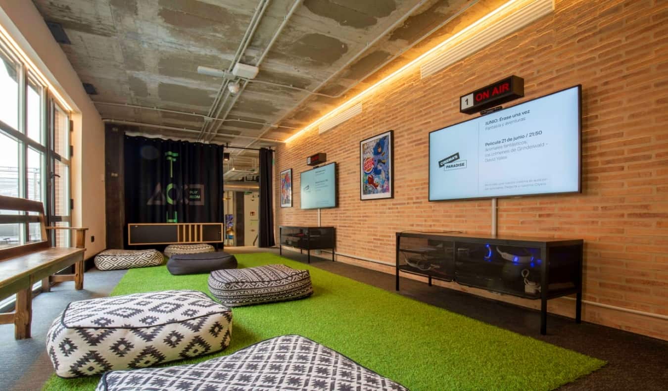 Games room with large flat-screen TVs and lots of stone bag chairs at The Inside House Lavapies, a hostel in Madrid, Spain.