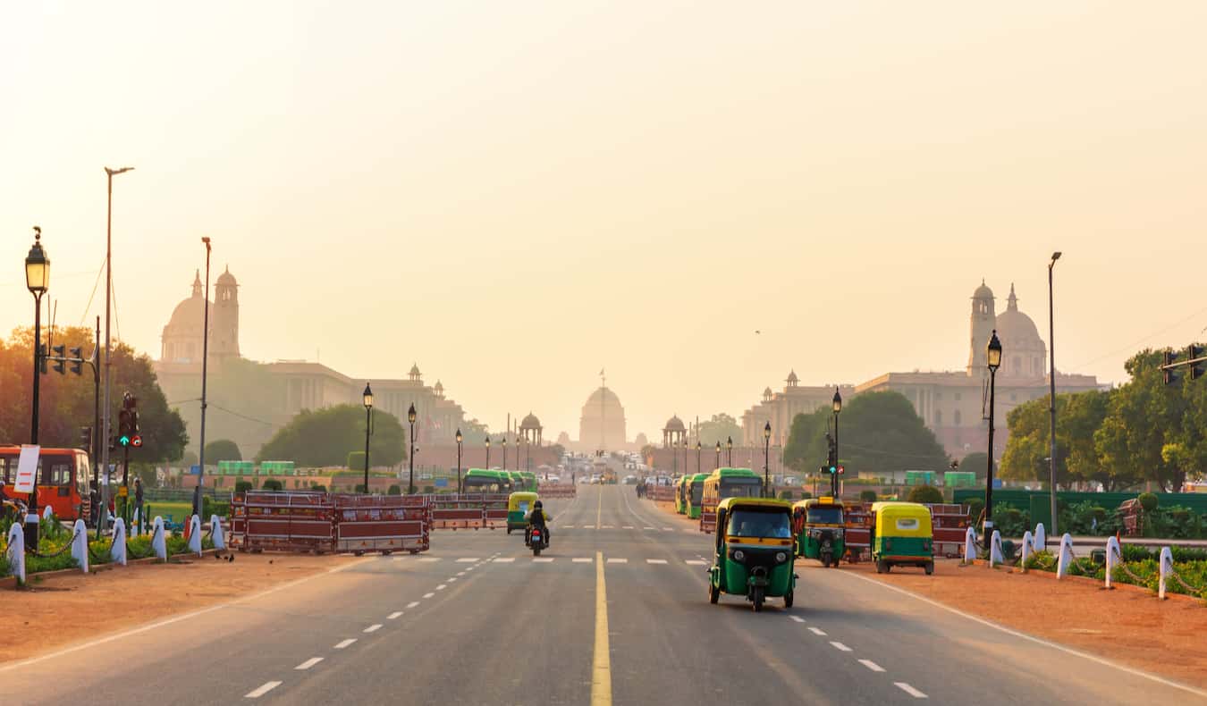 A busy road in India with the sun setting and smog and dust in the air