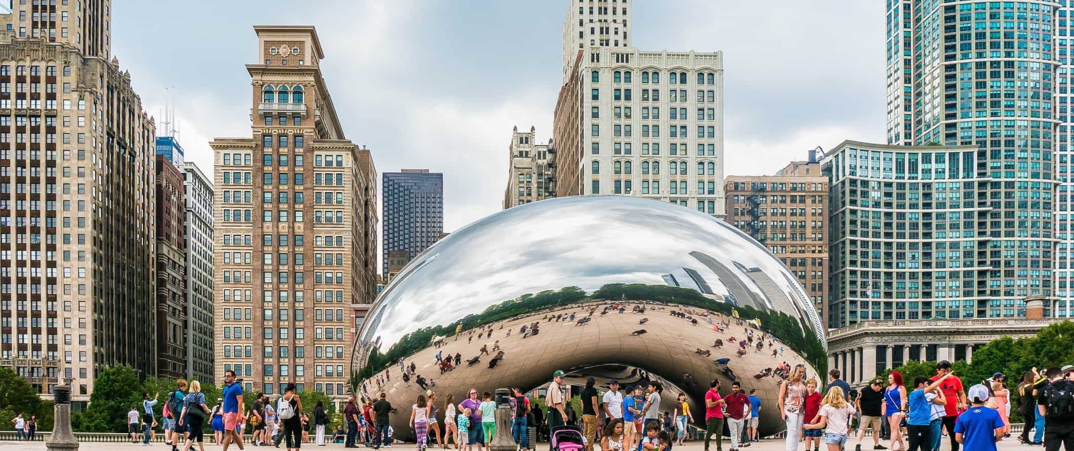 The huge, reflective chrome bean with people surrounding and tall buildings behind it in Chicago, USA.