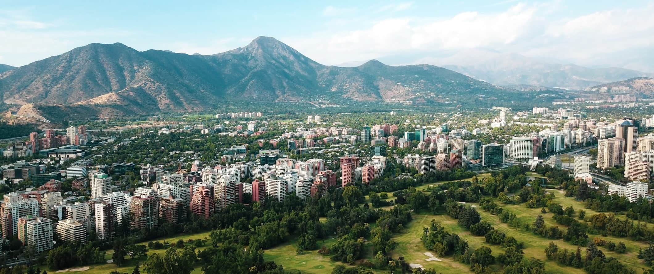 The city of Santiago nestled in a valley with mountains rising up behind the tall buildings in Chile