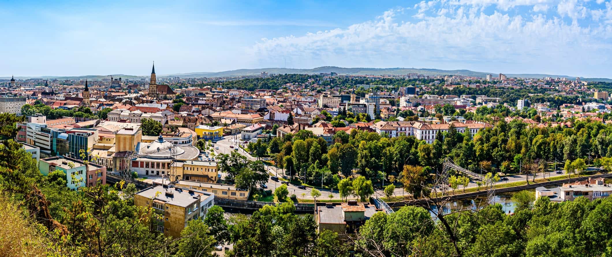 Aerial view of the skyline and rooftops, with a river running through, in the city of Cluj-Napoca, Romania