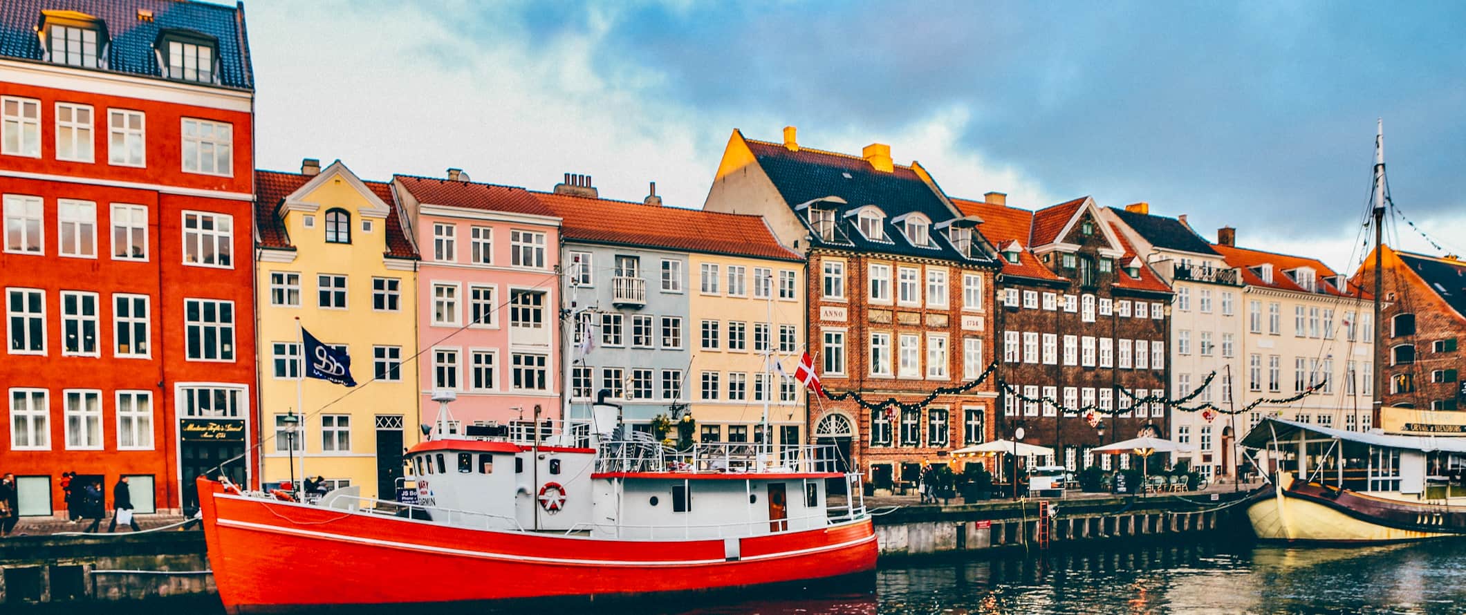 More colorful buildings along a canal lined with boats in Copenhagen, Denmark