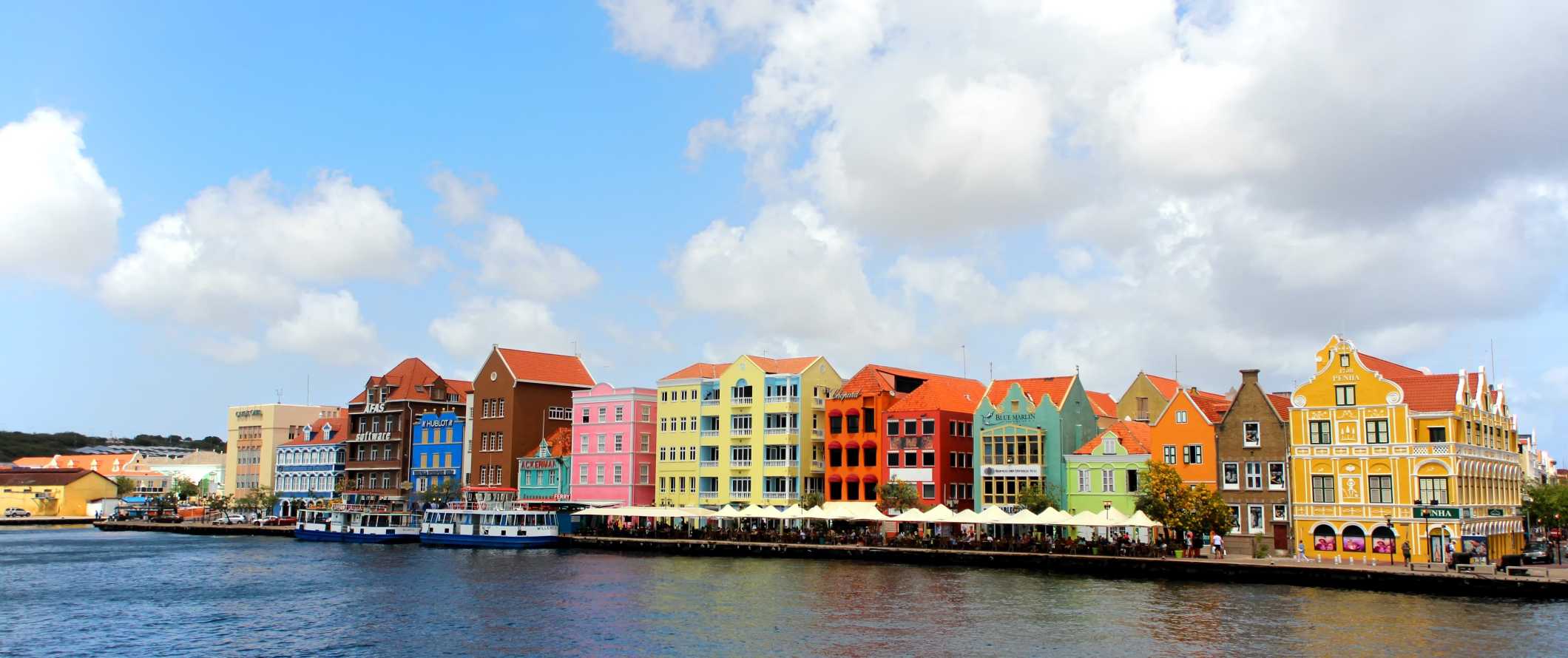 Brightly colored houses and people dining outside on the waterfront on the tropical island of Curaçao in the Caribbean