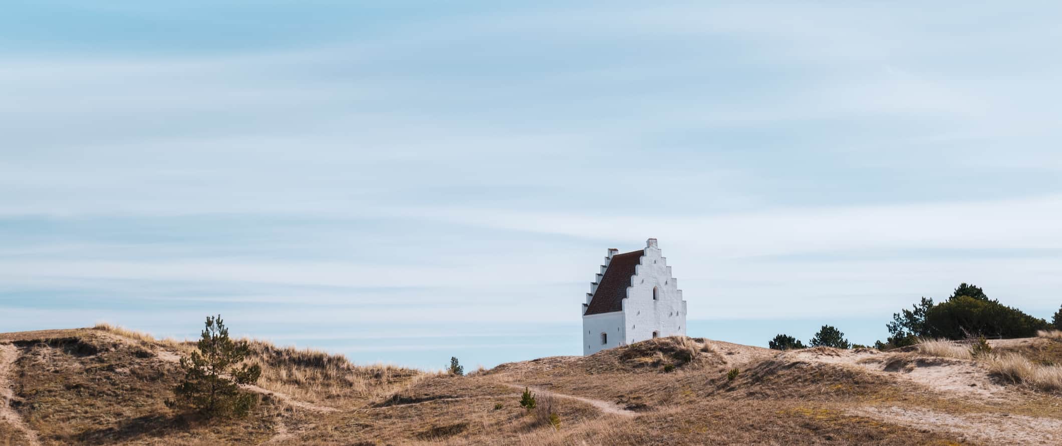 A small, white church on the rugged, wind-blown shores of Jutland in Denmark