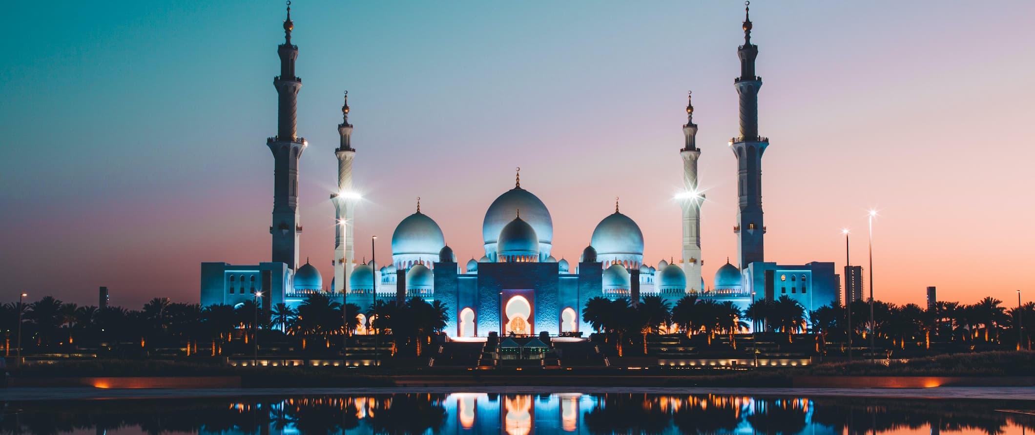 A huge mosque lit up at night near the water of Dubai