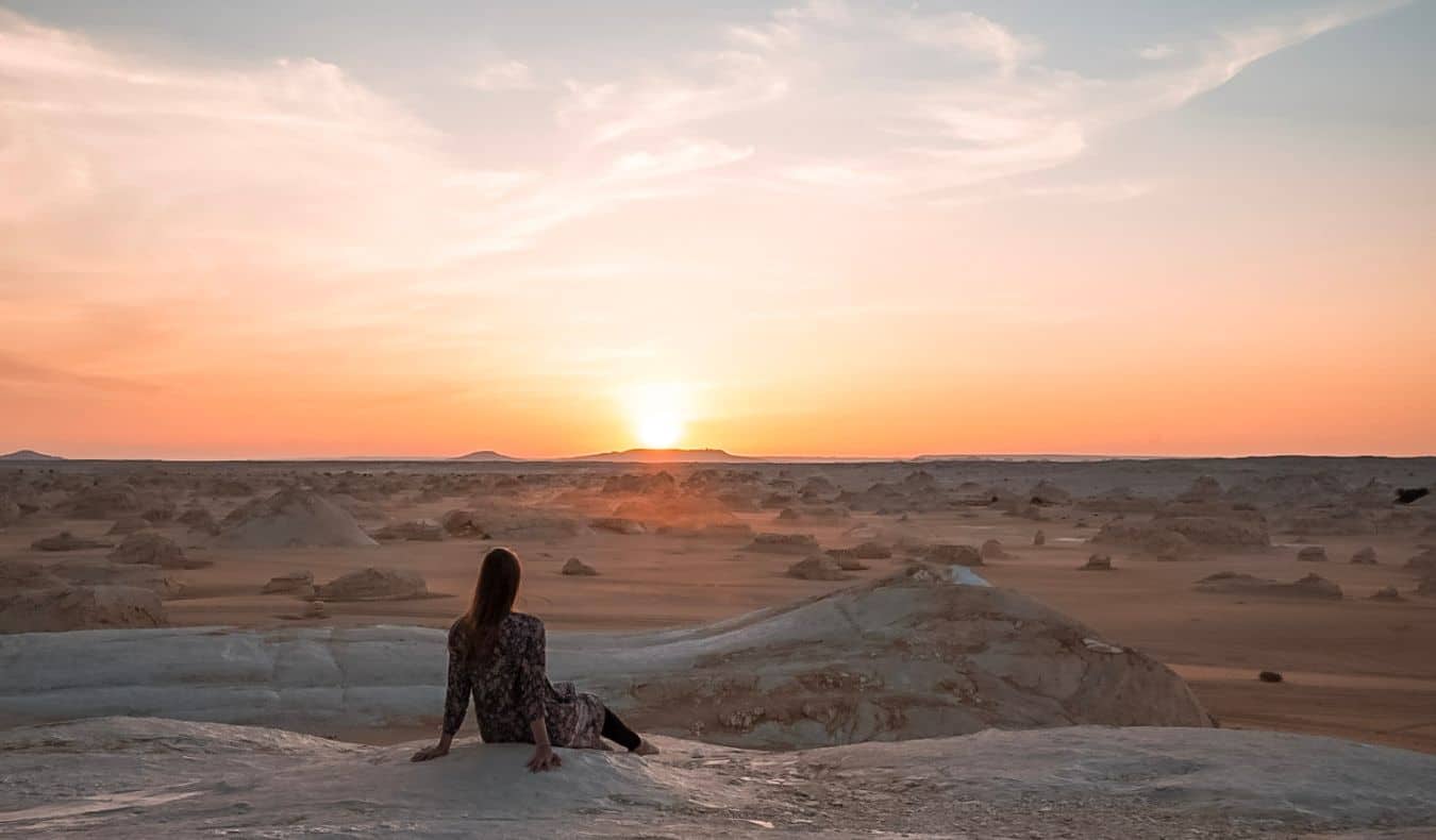 A solo female traveler posing in the desert of Egypt at dusk