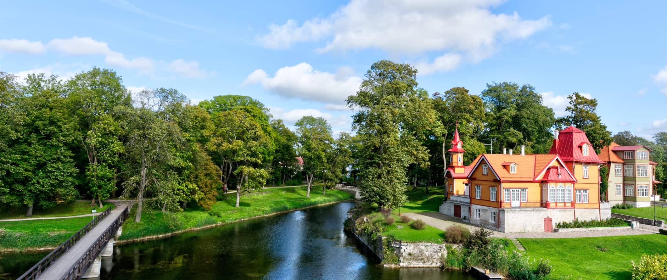 Brightly colored building along a tree-lined canal in the countryside of Estonia