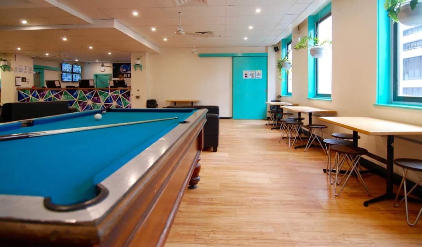 Common area with tables and pool table at Flinders Backpackers hostel in Melbourne, Australia.