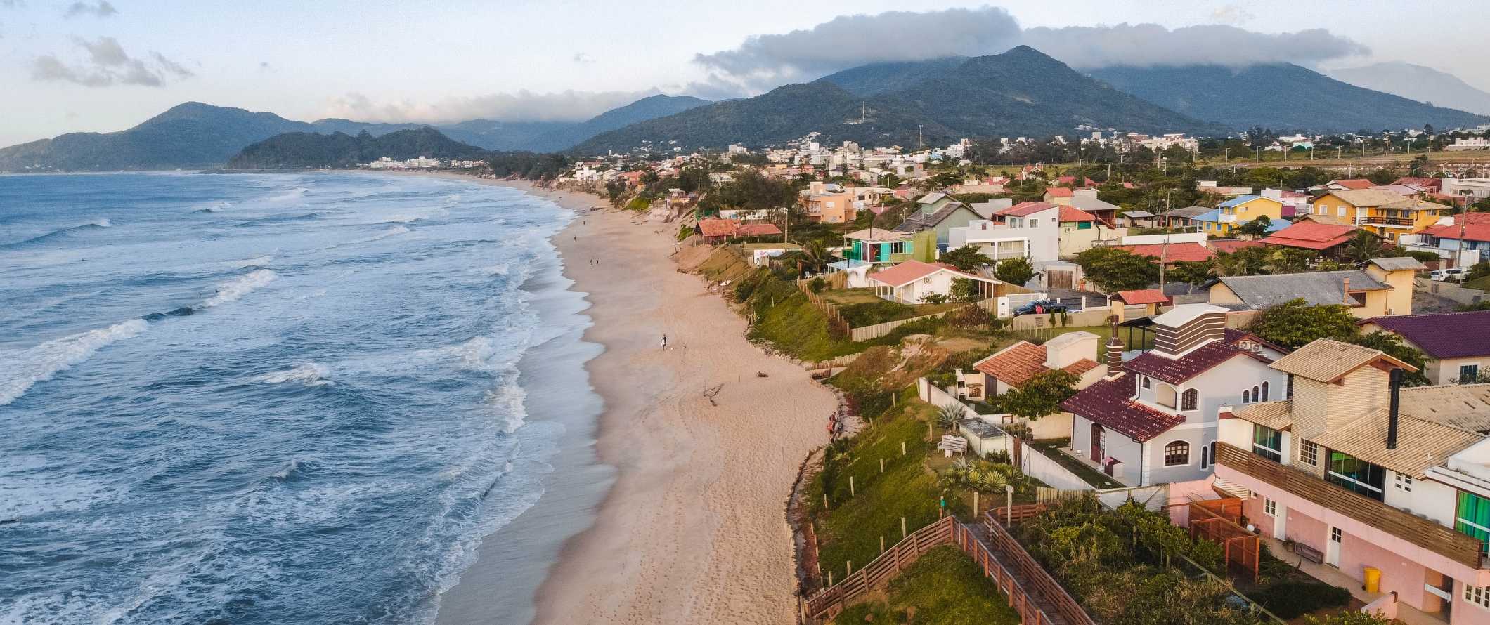 Colorful houses along the beach with mountains in the background in Florianópolis, Brazil