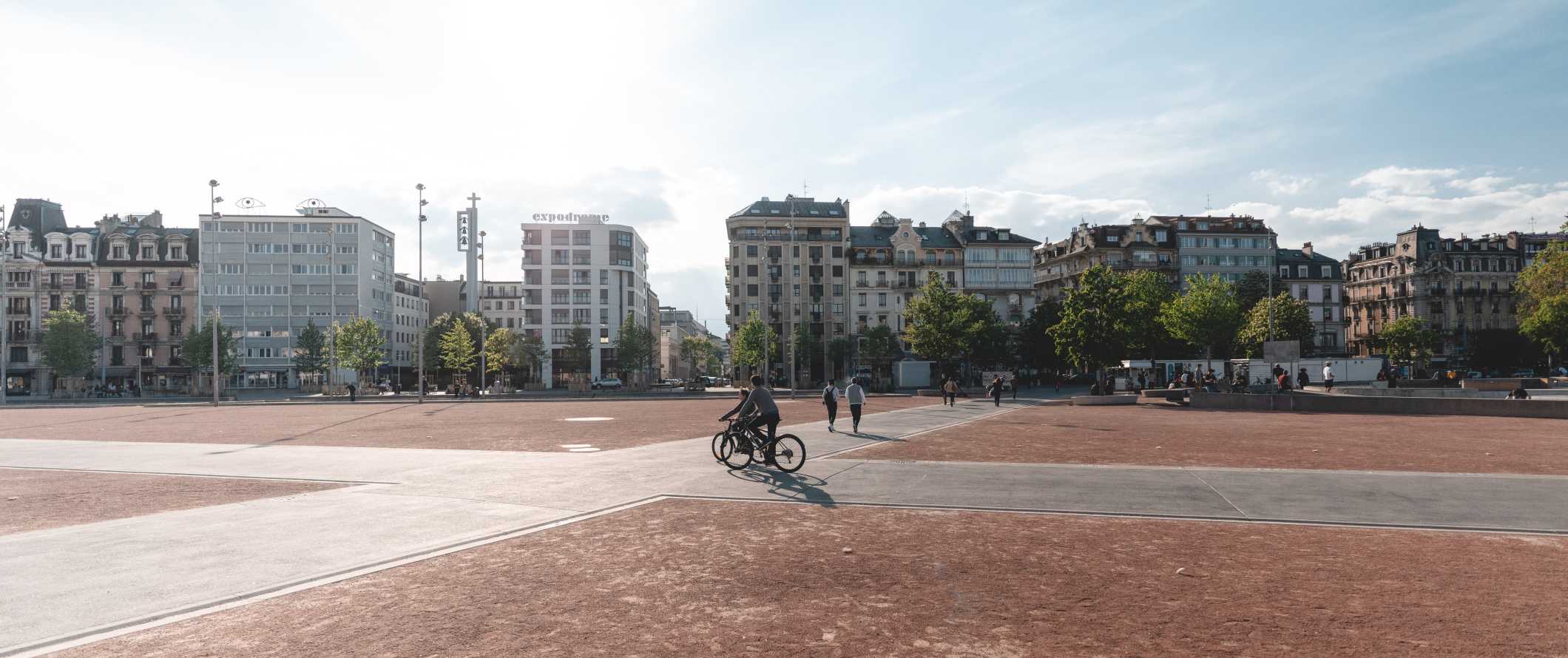 People walking and biking through a large plaza in Geneva, Switzerland