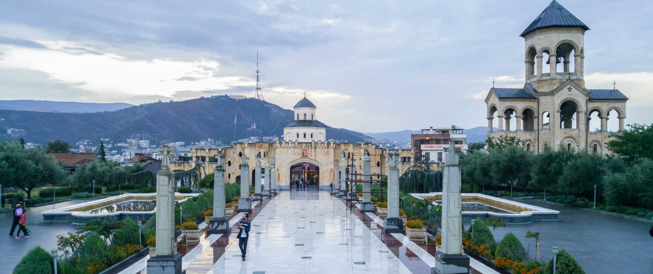 People walking down a pathway in front of the Holy Trinity Cathedral of Tbilisi, Georgia