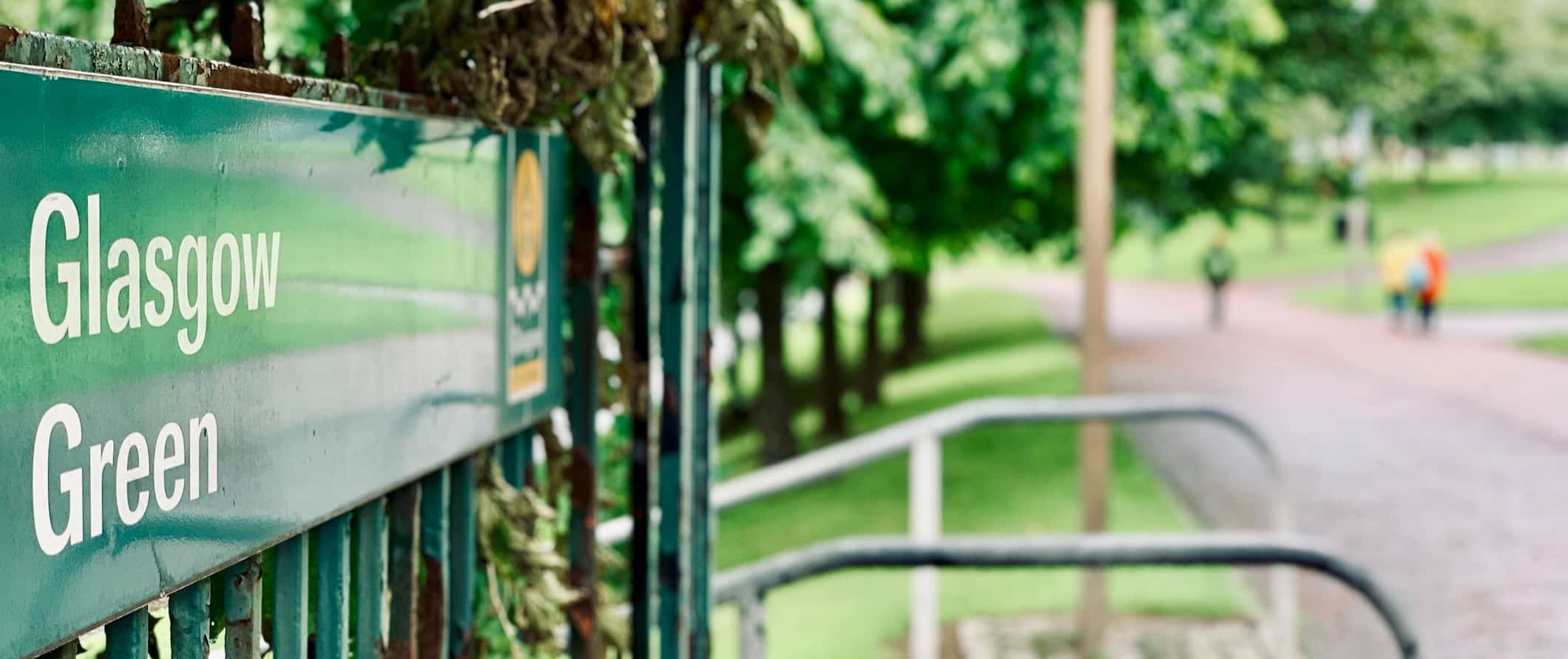 A sign on a bench pointing to the Glasgow Green in Glasgow, Scotland on a sunny summer day