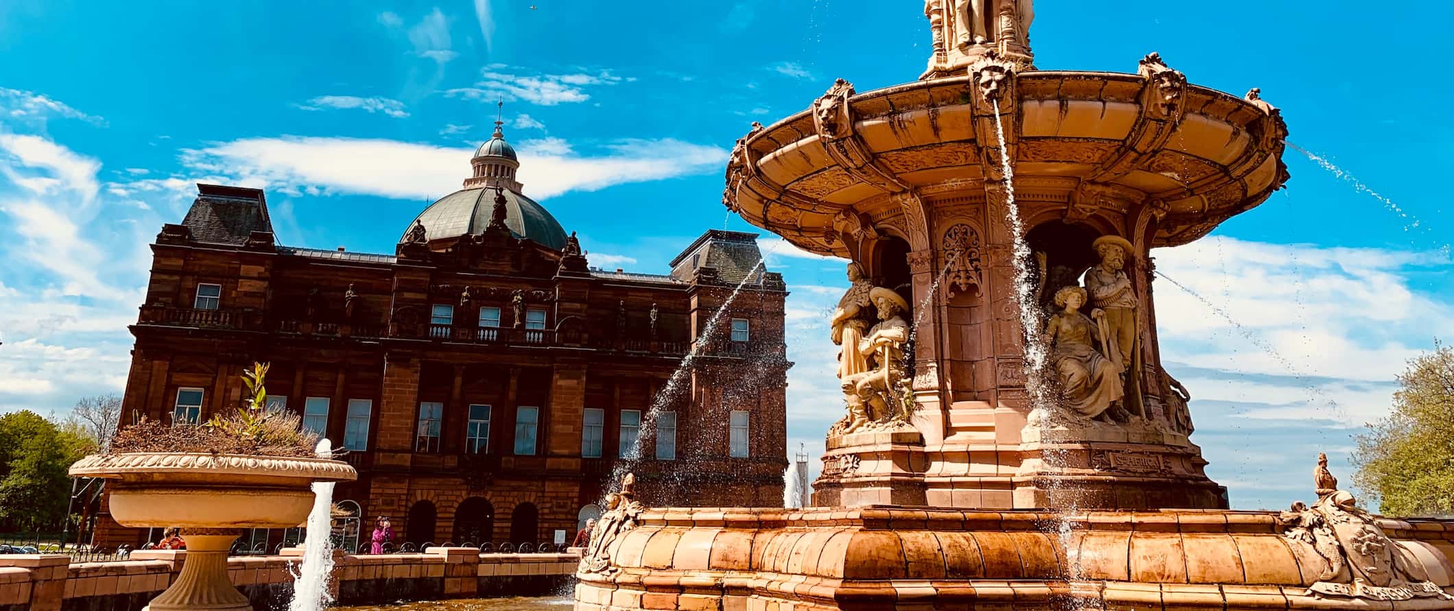 Historic buildings and an old fountain in Glasgow, Scotland on a sunny summer day