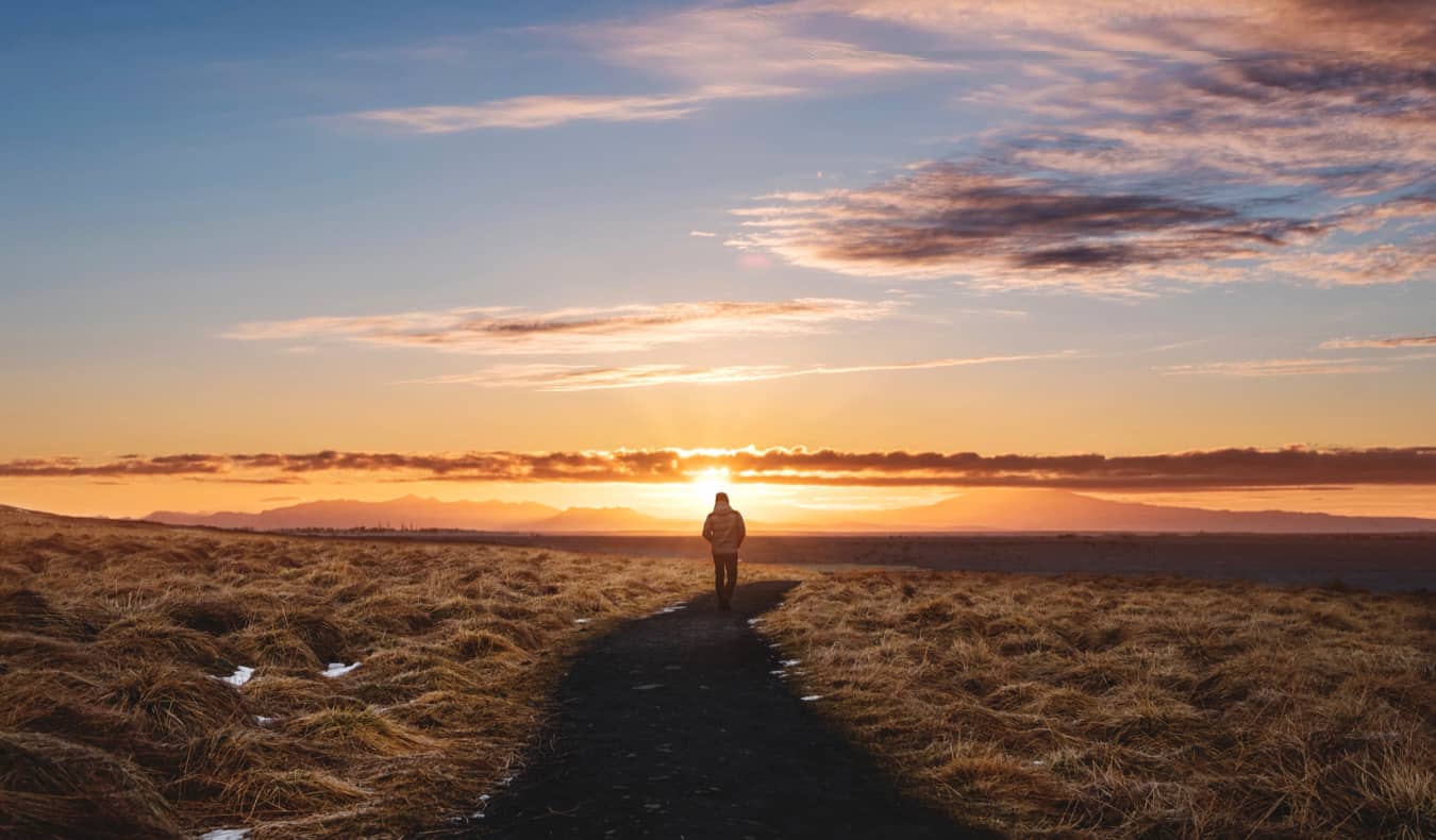 A traveler walking into the sunset on a hiking trail overseas