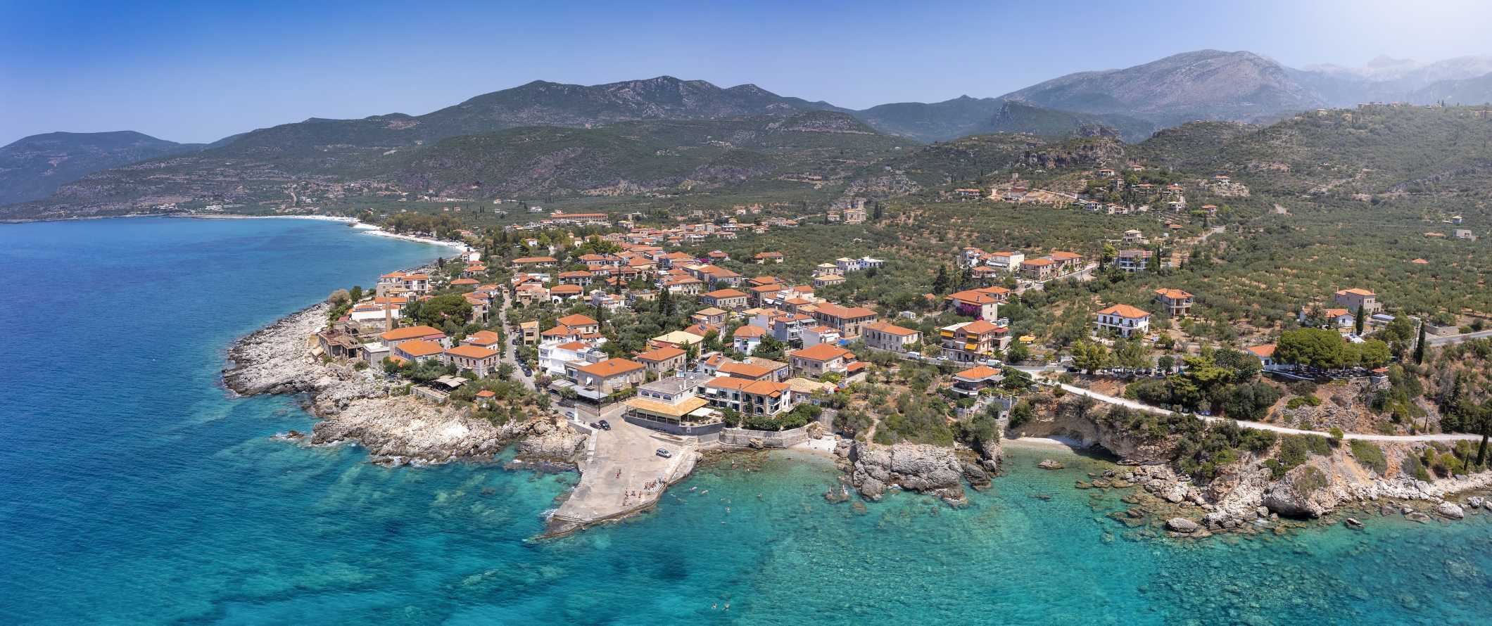 Aerial view of  Greek town along the Mediterranean ocean, with mountains in the background