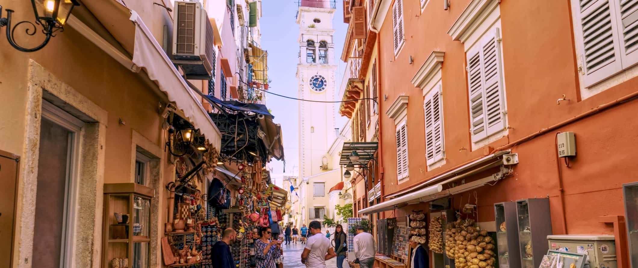 View of a bell tower at the end of the busy narrow streets in the city of Corfu, Greece.