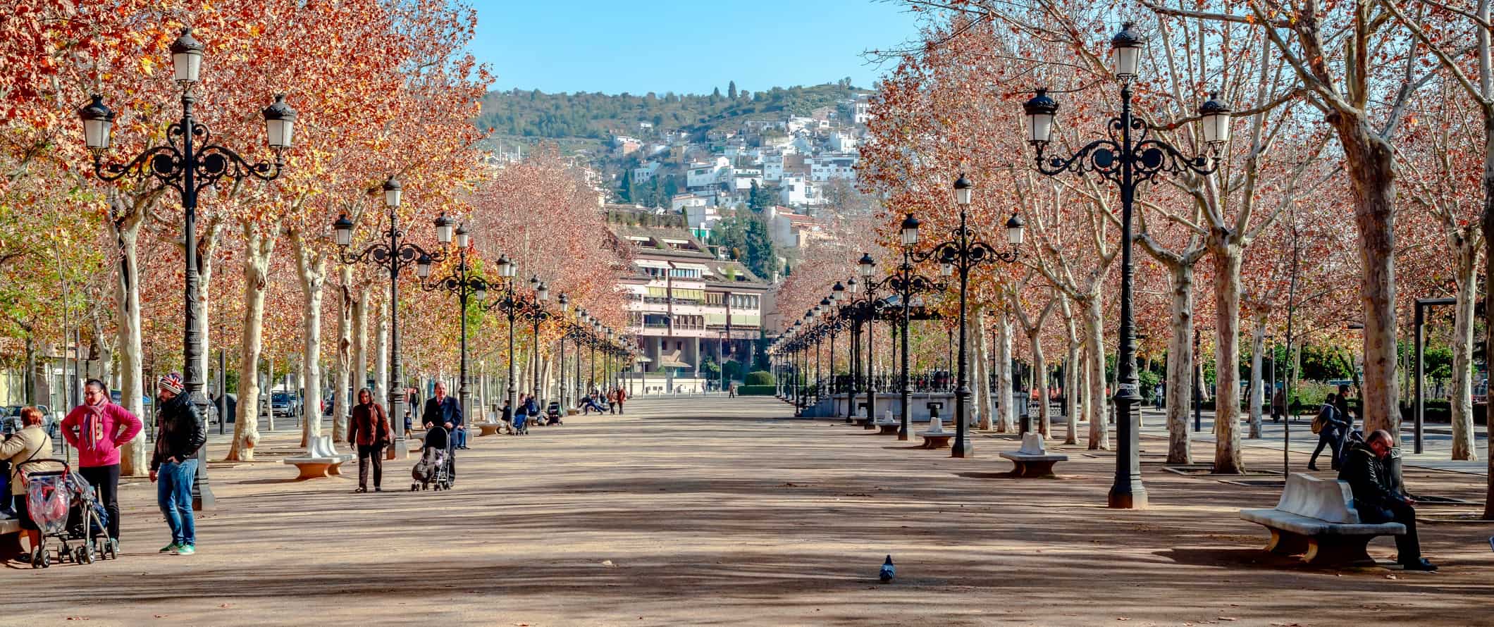 People walking and biking along a wide path on a warm day in Granada, Spain