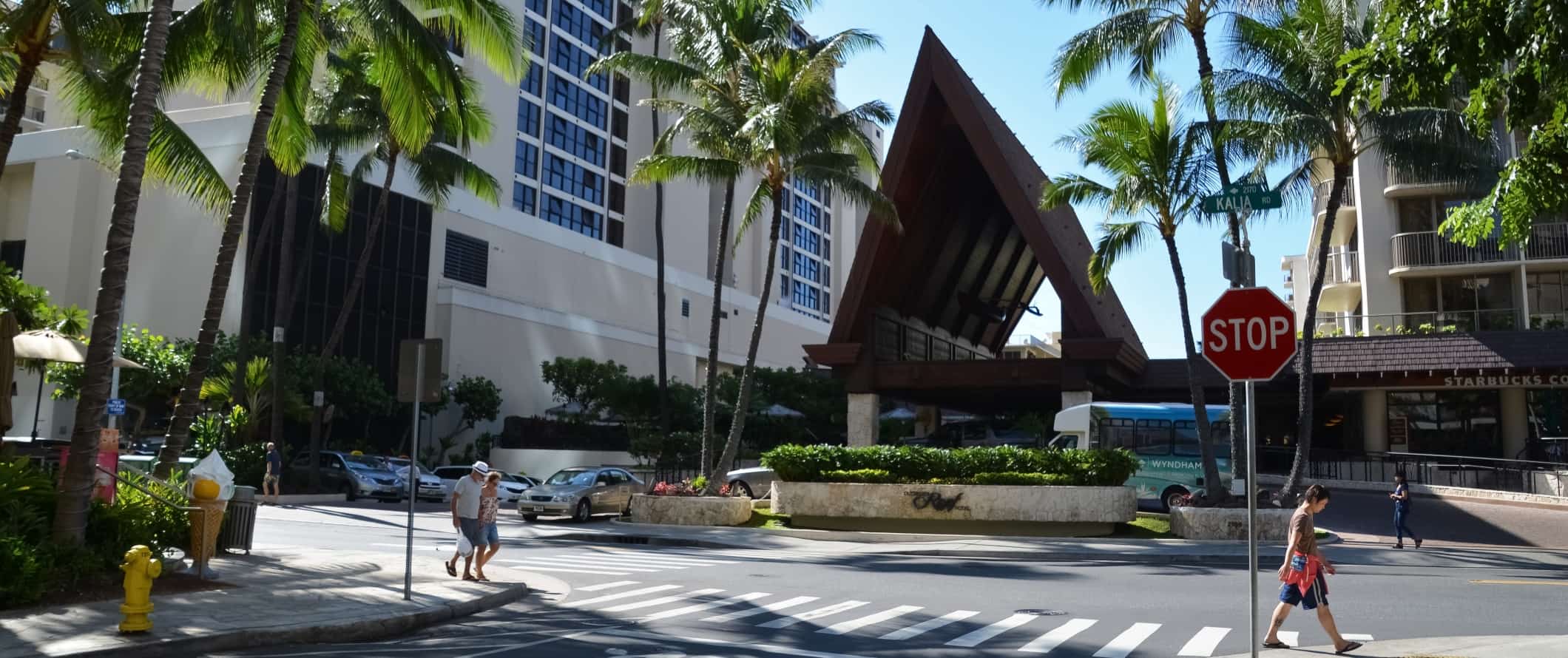 People walking down the street under palm trees in Honolulu, Hawaii.