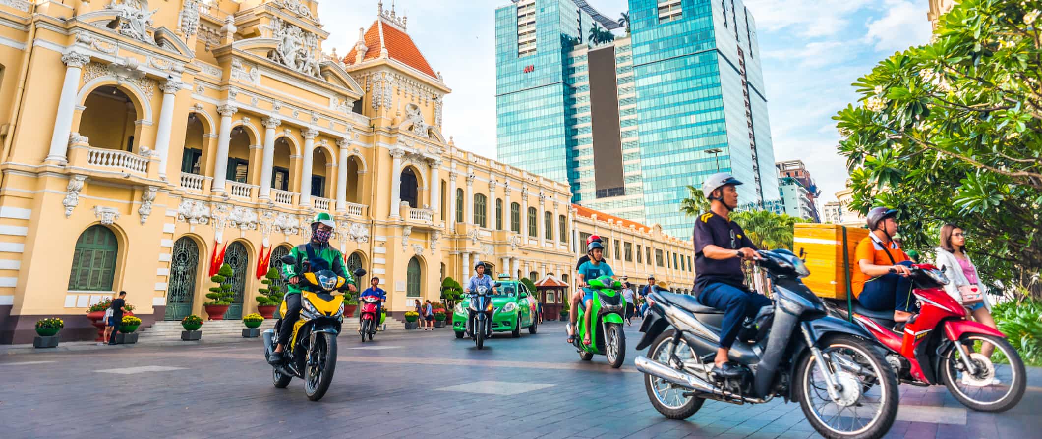 Locals riding scooters and mopeds on a busy street in Ho Chi Minh City, Vietnam near the city hall