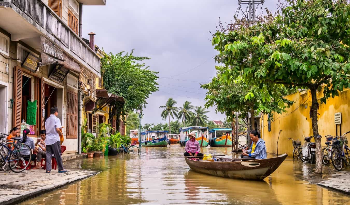 Women sitting in a boat with people on the sidewalk of buildings nearby in Hoi An, Vietnam“/><br />
<strong>Hoi An</strong> – I fell in love with Hoi An on my first visit. I loved spending time by the river, strolling through the narrow streets of the Old Town strung with colorful lanterns, watching the sunset, and drinking cheap beer. The city is packed with picturesque historical homes, pagodas, and street-side cafés. </p>
<p>It’s also an extremely popular place for ordering tailored clothing, which is one of the main reasons people come here. You can get anything made here — from custom-made suits to gowns to sundresses to leather boots to sneakers. The tailor shops will even mail all your goods home to you.</p>
<p>Otherwise, Hoi An makes for a relaxing destination in an otherwise hectic country, with the beach only a 15-minute bike-ride from town. </p>
<p>Some of the top things to do here include the following: </p>
<ul>
<li><strong>Explore My Son:</strong> – This is one of the most important sites relating to the ancient Kingdom of Champa and is said to have been Vietnam’s religious and intellectual center. Even in their ruined state, the remaining Hindu temple structures are impressive.</li>
<li><strong>Relax on the beach</strong> – An Bang and Cua Dai beaches are both close to Hoi An and great places to spend an afternoon. Cua Dai is designated as one of Vietnam’s five UNESCO World Heritage sites; both beaches offer soft white sand and excellent beachside restaurants. </li>
<li><strong>Attend the Full Moon Festival</strong> – Hoi An’s Full Moon Festival is held on the 14th day of the lunar cycle each month and is probably the best time to visit the city, if you don’t mind the crowds. This is a fun time to party with locals, as the streets come alive with folk music, plays, and dancing!</li>
</ul>
<p><strong>Where to Stay</strong>: <a href=