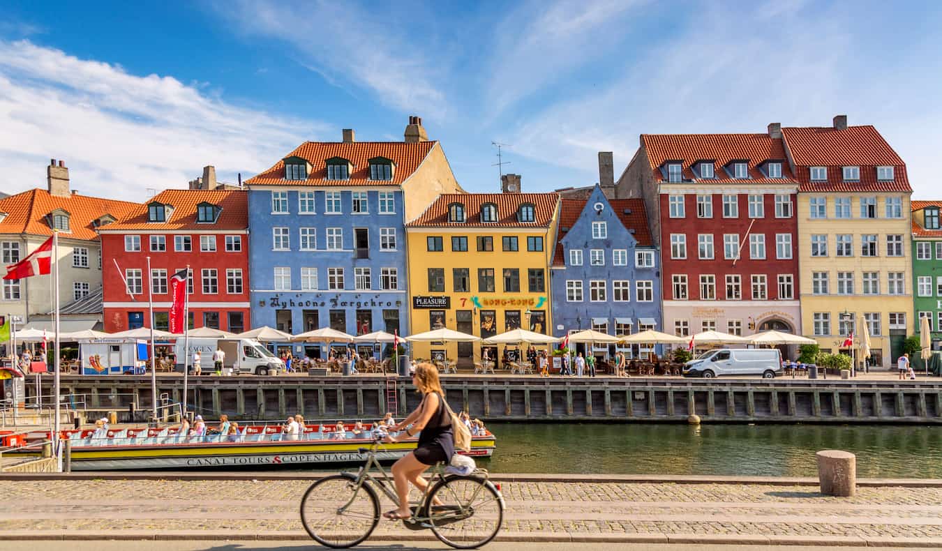 Colorful Copenhagen buildings by the water when someone drives by