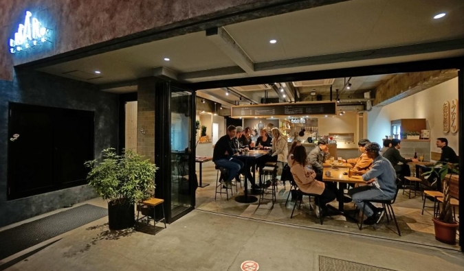 People sitting and talking in the bar as seen through the floor to ceiling windows at Imano Tokyo Hostel in Tokyo, Japan