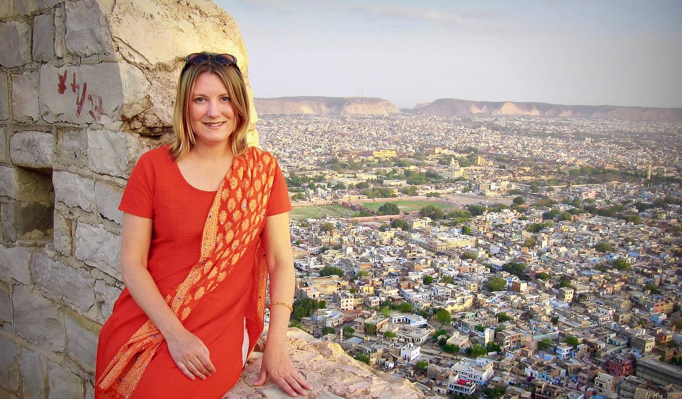 A solo sexuality traveler in India posing near a historic wall overlooking a town