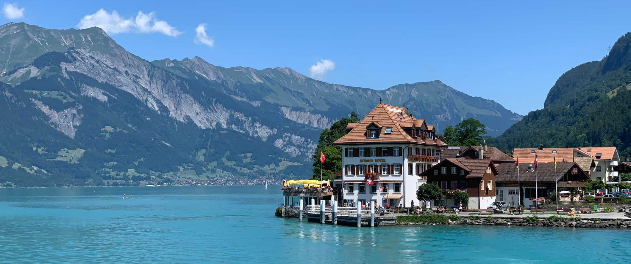 A hotel on the edge of a bright blue lake surrounded by mountains in Interlaken, Switzerland
