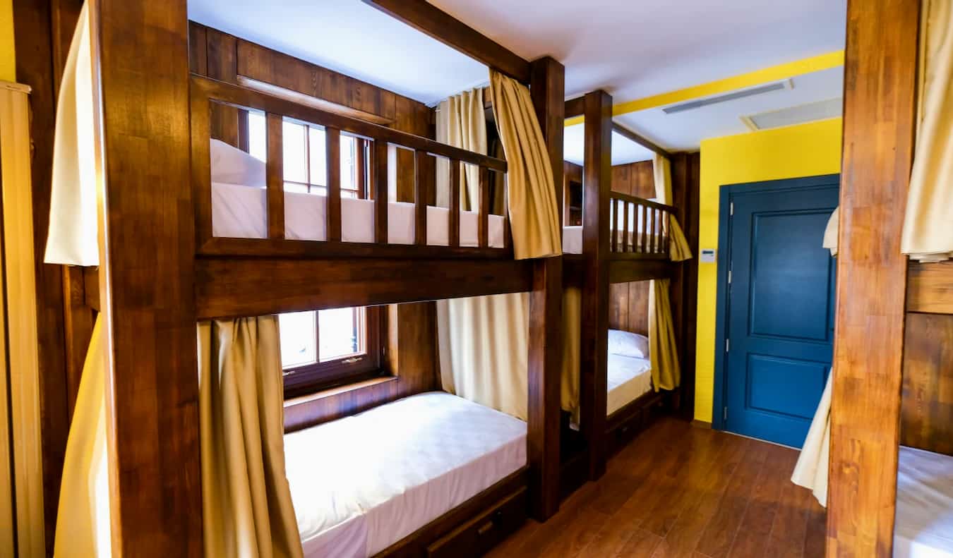 The interior of Yolo Hostel in Istanbul, Turkey, with wooden bunk beds and curtains in a small dorm room