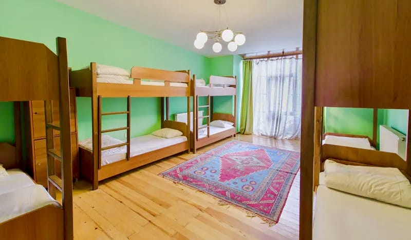 녹색 벽과 아늑한 이층 침대가 있는 Cheers Hostel의 호스텔 도미토리