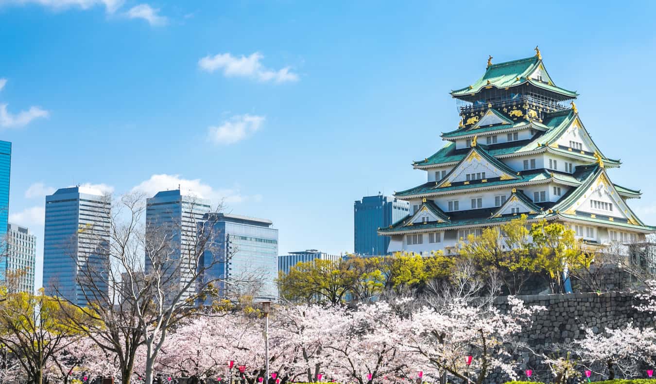 The iconic, towering Osaka Castle overlooking busy Osaka, Japan on a sunny day