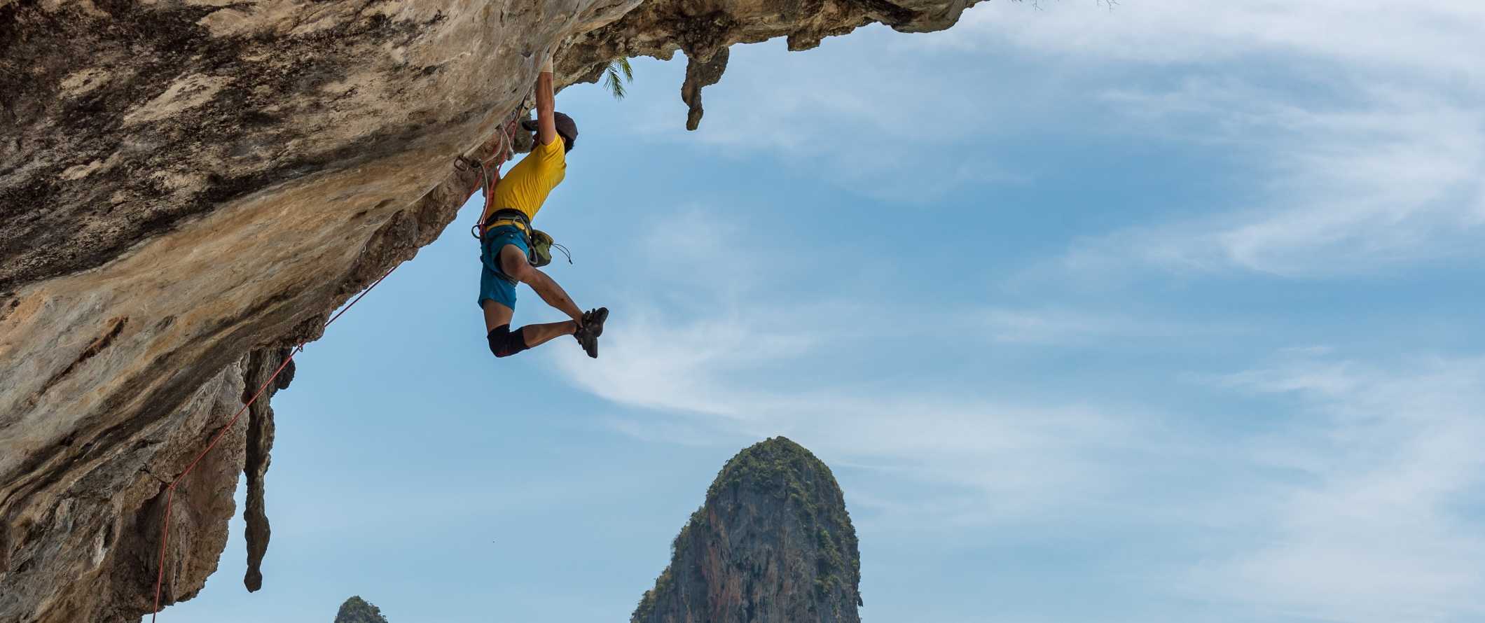Rock climber scaling a limestone wall in Ko Phi Phi, Thailand