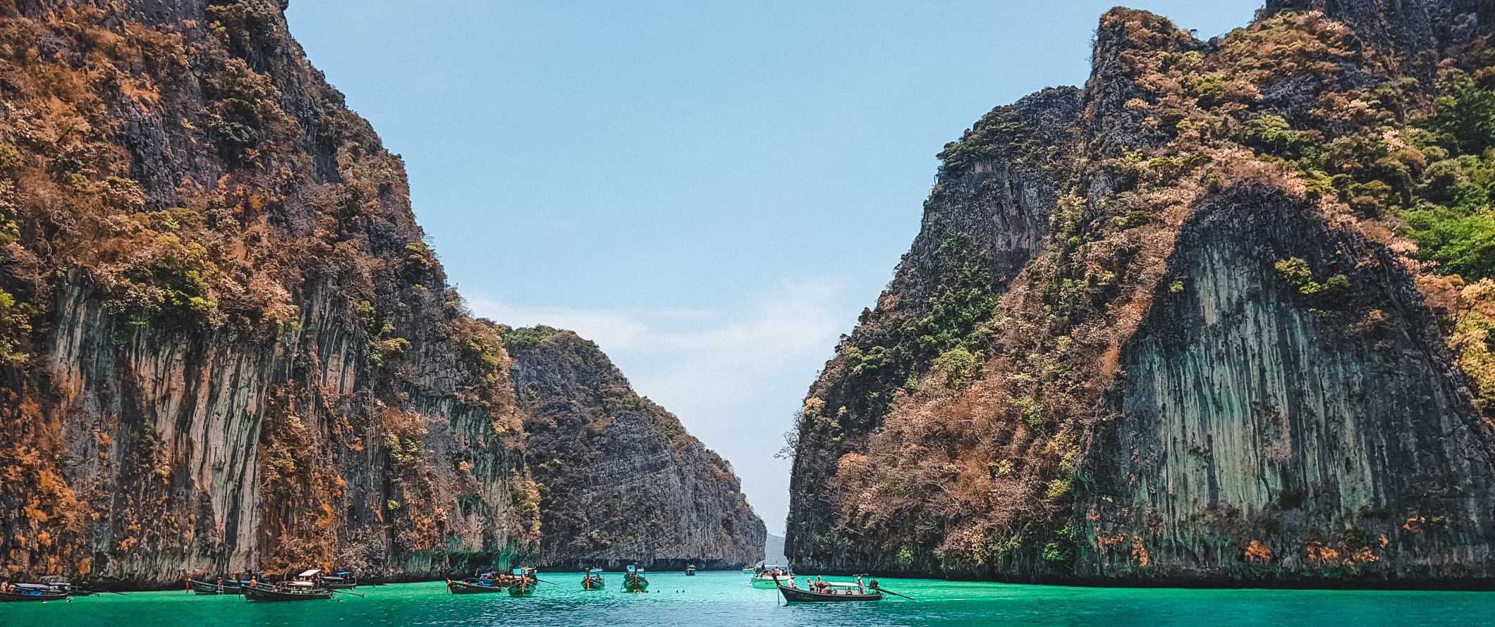 Boats in the water in front of huge limestone formations in Maya Bay on the island of Ko Phi Phi, Thailand