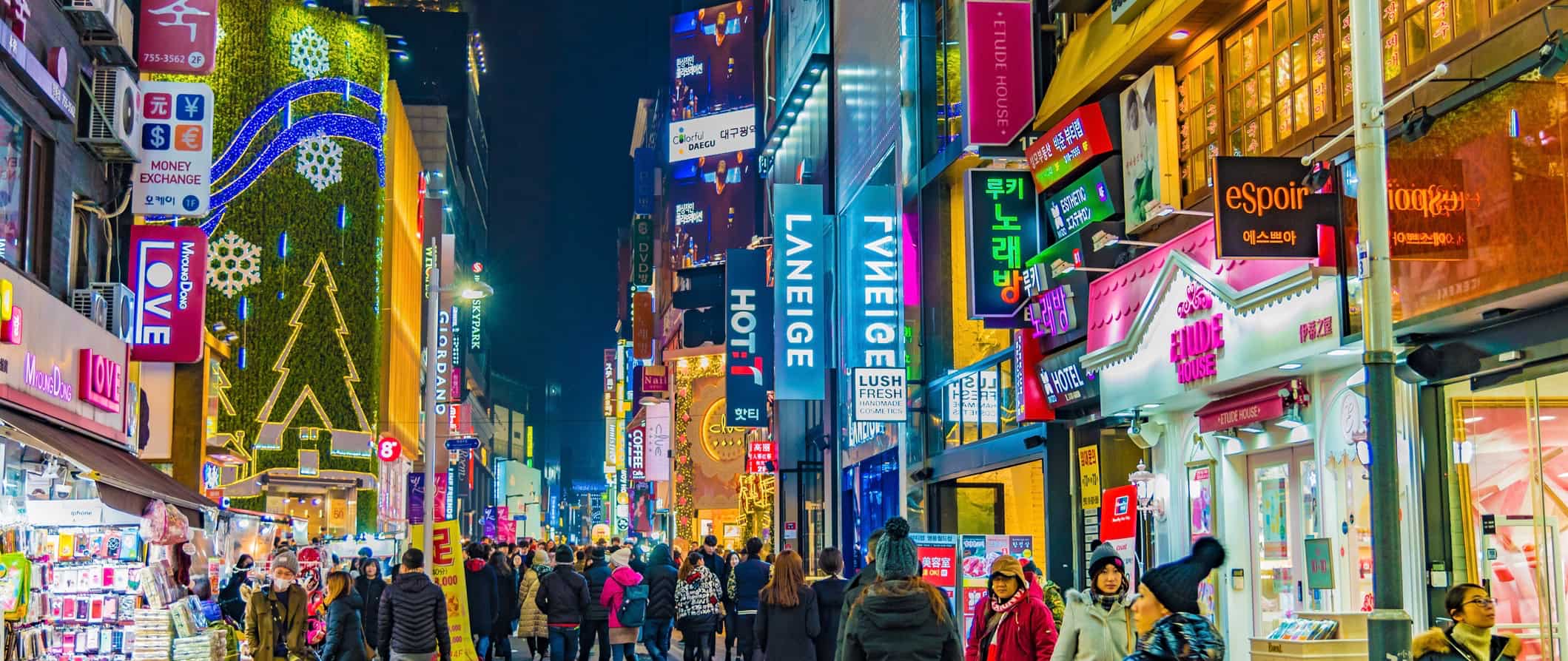 Locals and tourists on a busy street in Seoul Korea at night with lots of bright signs