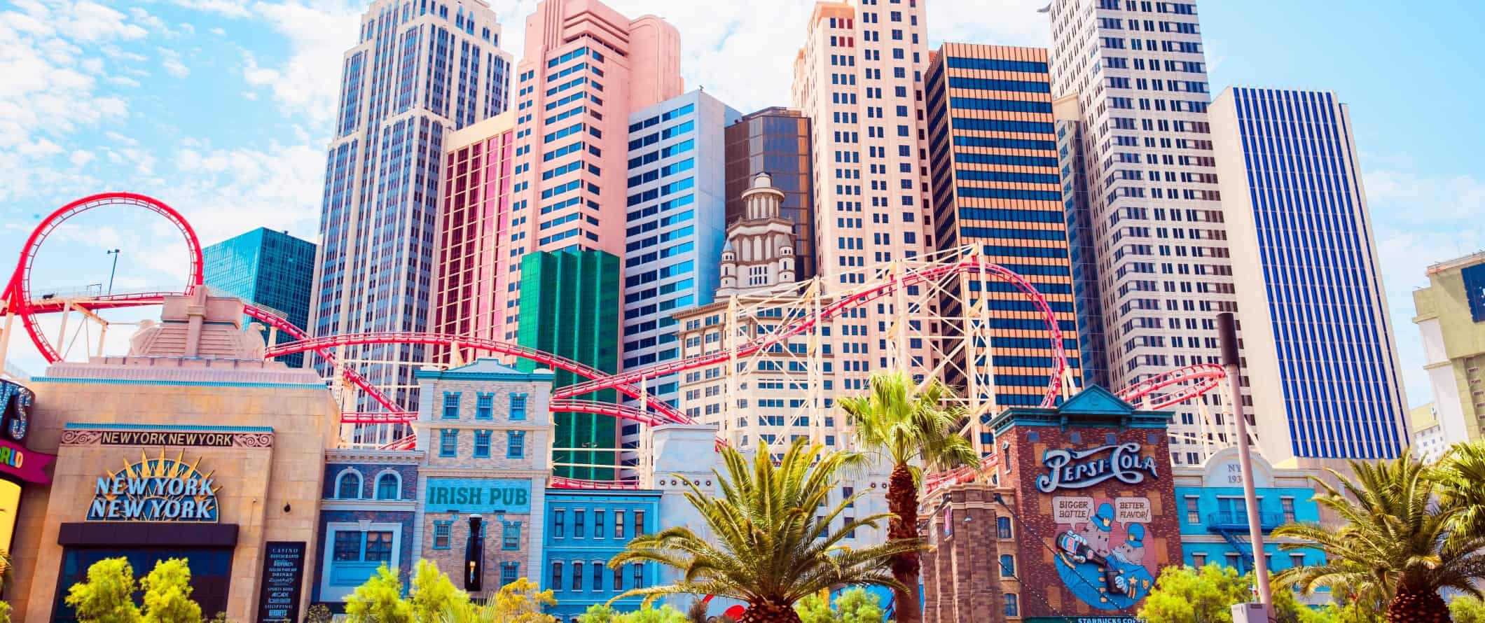 Tall skyscrapers in the background, a roller coaster, and low, historic buildings in the foreground in Las Vegas, Nevada.