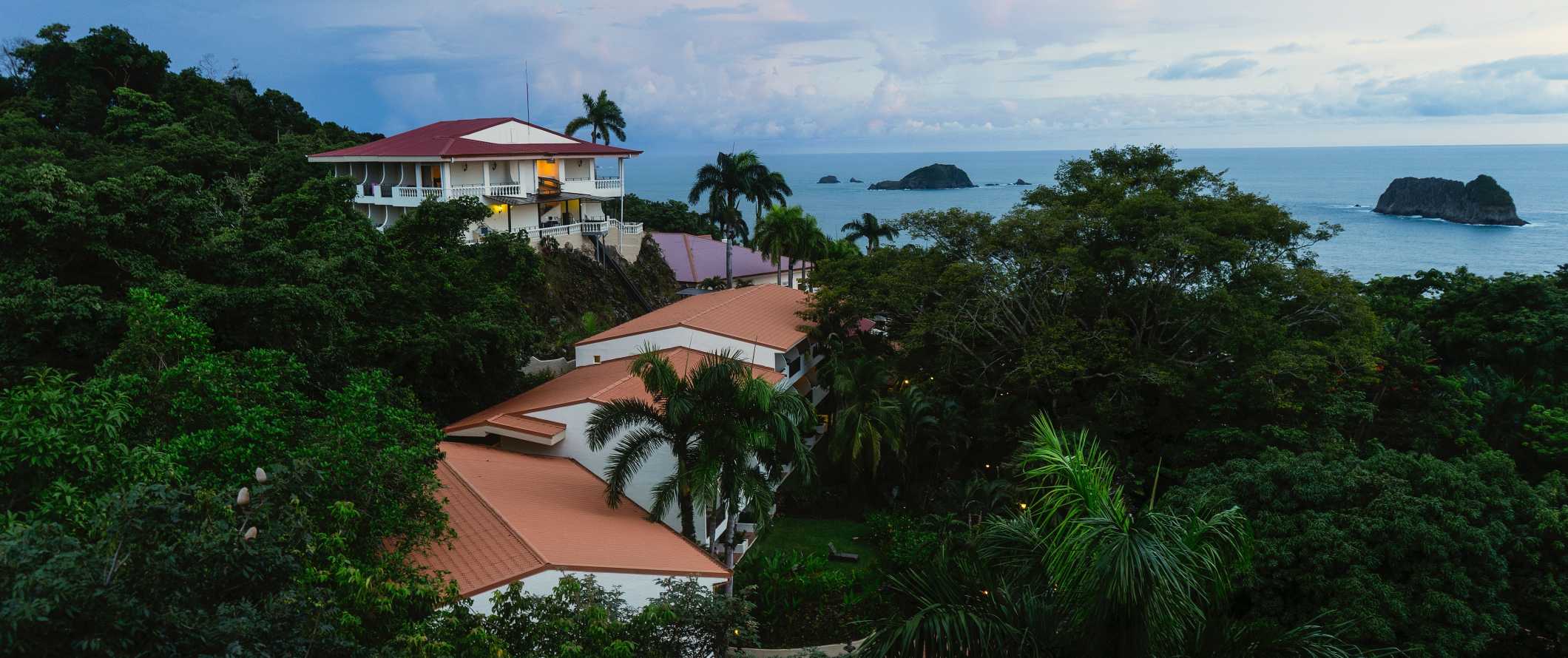 Small resort and hotel buildings nestled in the rainforest with the ocean in the background in Manuel Antonio, Costa Rica
