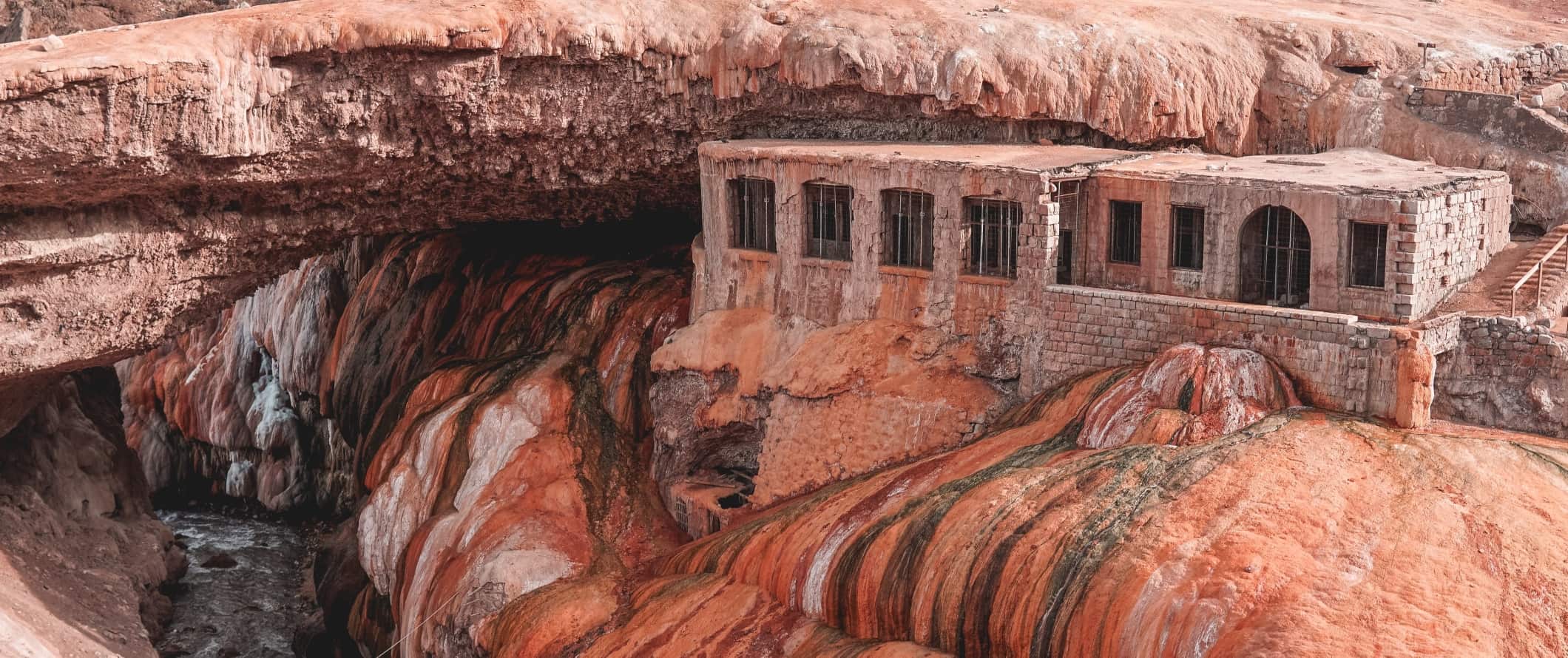 Historic brick building built into coppery-gold mineral deposits at Puente del Inca near Mendoza, Argentina