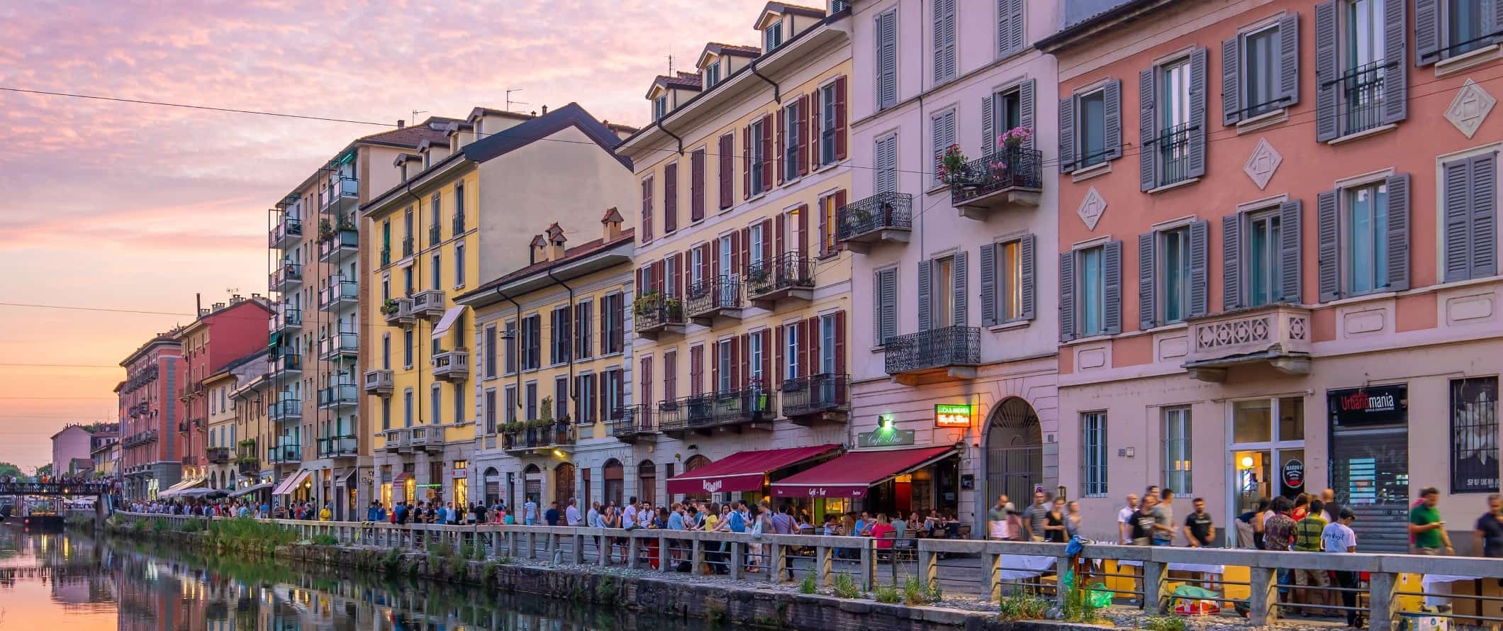Colorful buildings along a canal at sunset in the Naviglio Grande district in Milan, Italy.