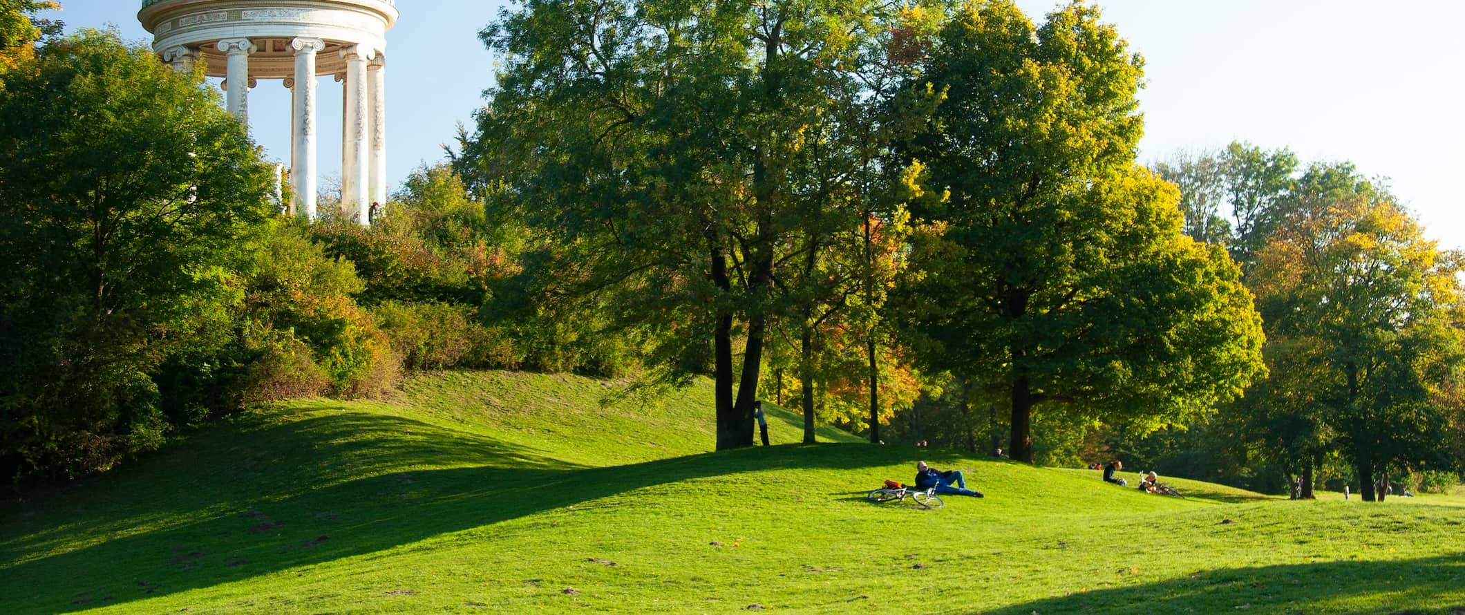 A lush green field with locals relaxing in the summer in Munich, Germany